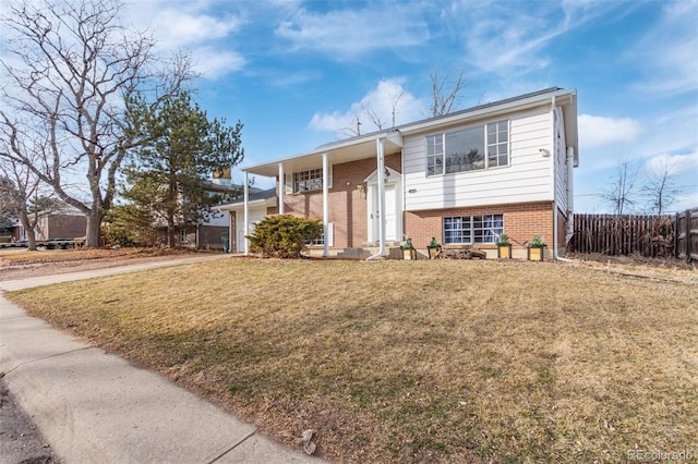 bi-level home featuring fence, a front lawn, concrete driveway, and brick siding