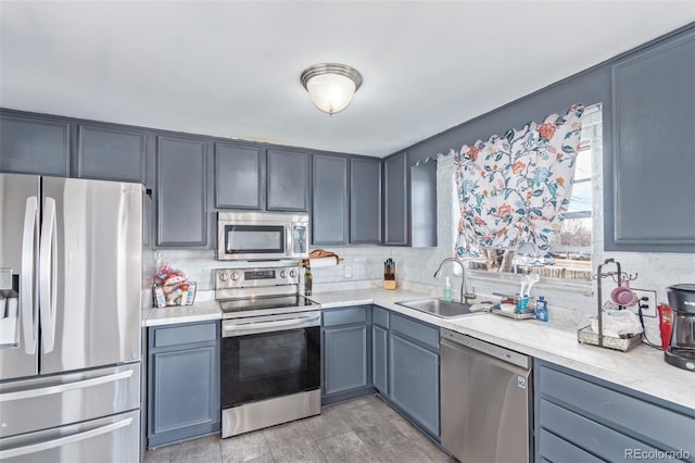 kitchen with light countertops, appliances with stainless steel finishes, backsplash, and a sink