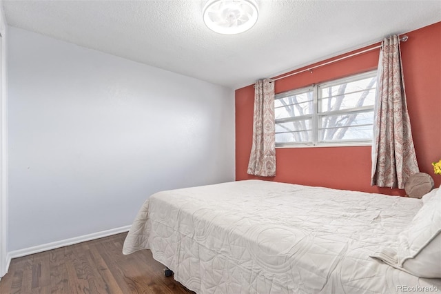 bedroom with a textured ceiling, baseboards, and wood finished floors