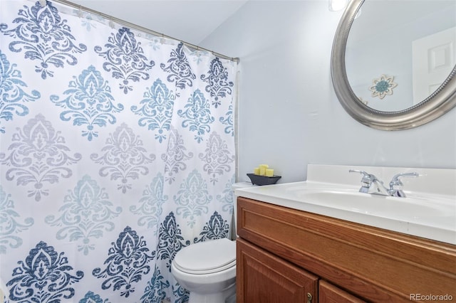 bathroom with curtained shower, vanity, and toilet