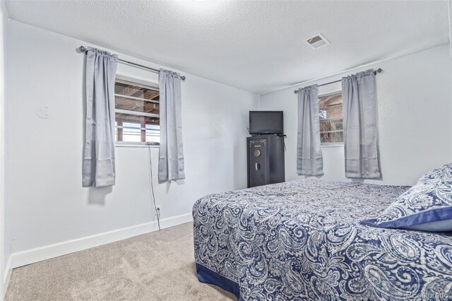 carpeted bedroom with a textured ceiling, visible vents, and baseboards