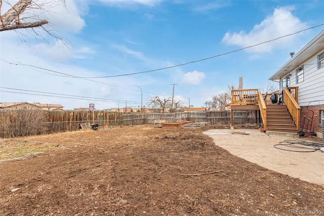 view of yard with a deck, a fenced backyard, and stairs