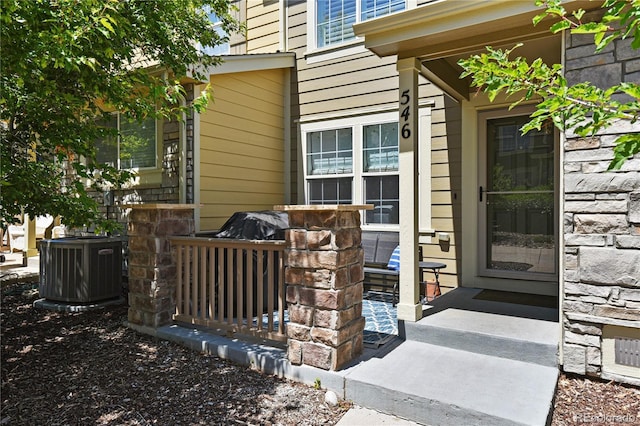 view of exterior entry featuring central AC unit and stone siding