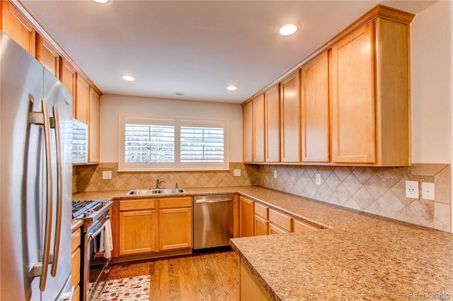 kitchen with recessed lighting, a sink, decorative backsplash, light wood-style floors, and stainless steel appliances