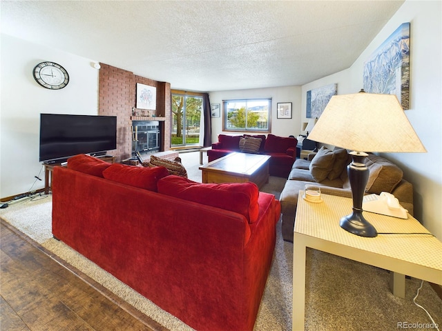 carpeted living room featuring a brick fireplace and a textured ceiling