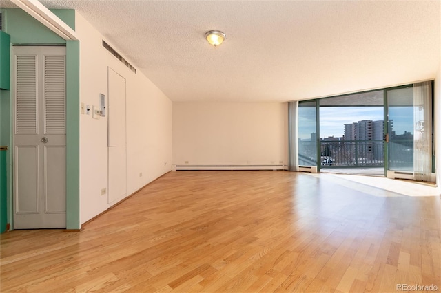 unfurnished room with floor to ceiling windows, baseboard heating, a textured ceiling, and light hardwood / wood-style flooring