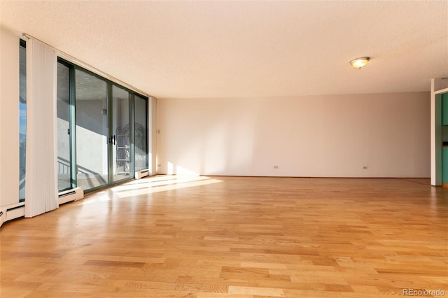 empty room with floor to ceiling windows, a baseboard radiator, light hardwood / wood-style floors, and a textured ceiling