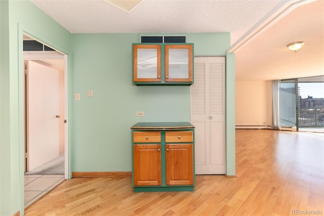 kitchen with a baseboard radiator, a textured ceiling, and light wood-type flooring