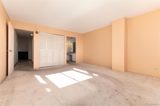 unfurnished bedroom featuring ensuite bathroom and light colored carpet