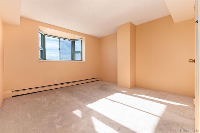 carpeted empty room with a textured ceiling and baseboard heating