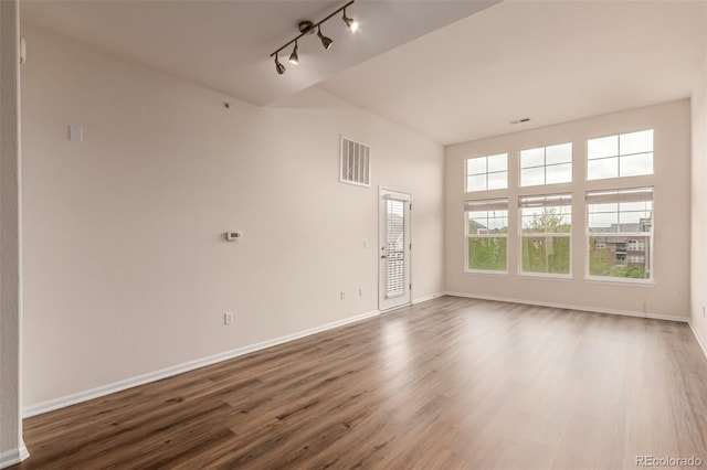 unfurnished room featuring track lighting, wood finished floors, and baseboards