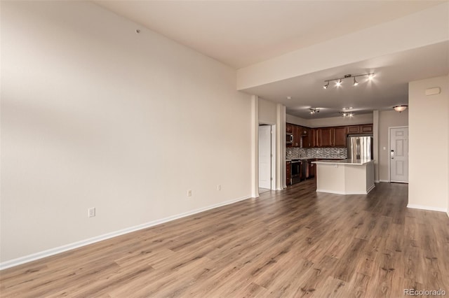 unfurnished living room with light wood-style floors, baseboards, and rail lighting