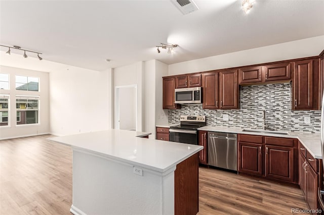 kitchen featuring track lighting, appliances with stainless steel finishes, a sink, and decorative backsplash