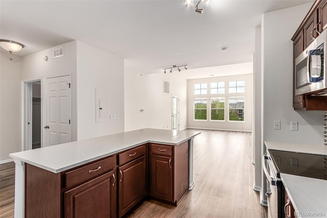 kitchen featuring electric range, track lighting, light wood-type flooring, and open floor plan