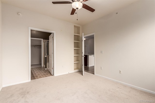 unfurnished bedroom with carpet flooring, baseboards, a walk in closet, ceiling fan, and a closet