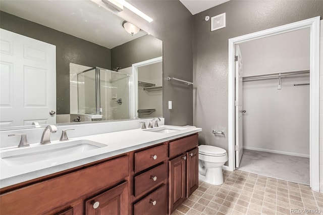 full bath featuring a shower stall, toilet, a spacious closet, double vanity, and a textured wall