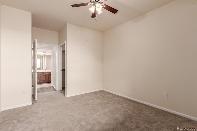 unfurnished bedroom featuring light carpet, baseboards, and ensuite bathroom