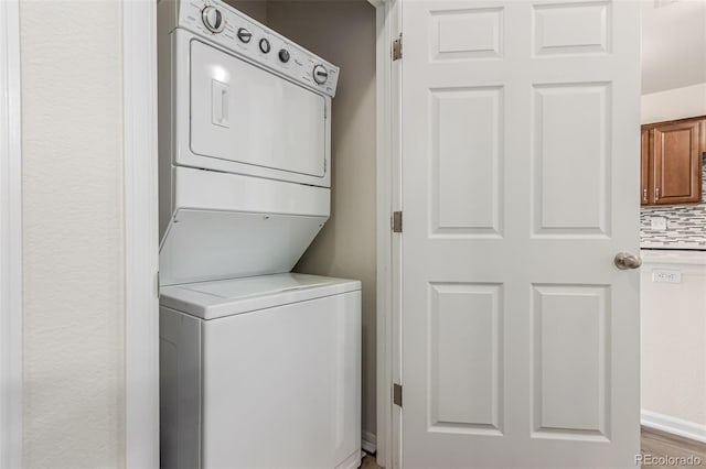 laundry area featuring stacked washing machine and dryer and baseboards