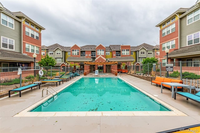 community pool featuring a residential view, fence, and a patio
