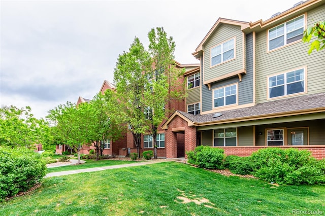 townhome / multi-family property with brick siding and a front yard