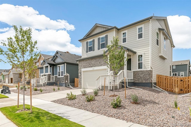 craftsman house with an attached garage, board and batten siding, fence, stone siding, and driveway