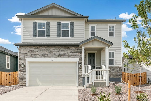 view of front facade with fence, an attached garage, concrete driveway, stone siding, and board and batten siding