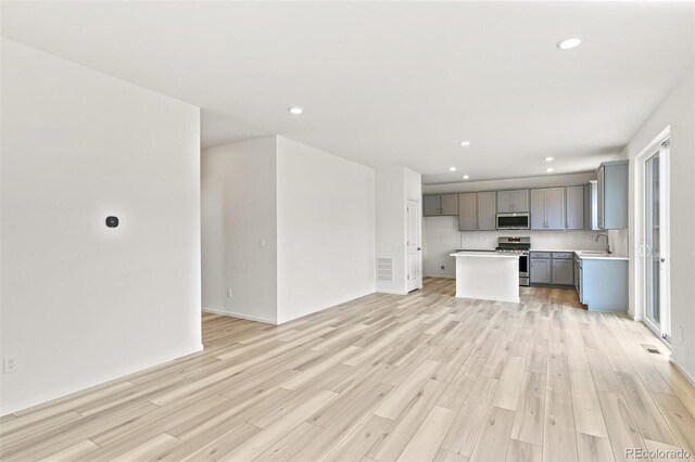 unfurnished living room with recessed lighting, light wood-style floors, visible vents, and a sink