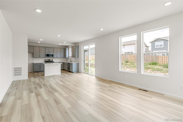 unfurnished living room featuring visible vents, recessed lighting, light wood-style floors, and a sink