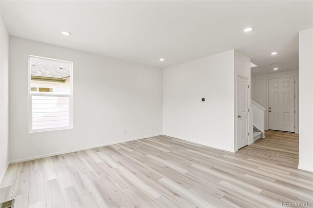 empty room with stairs, recessed lighting, and light wood-type flooring