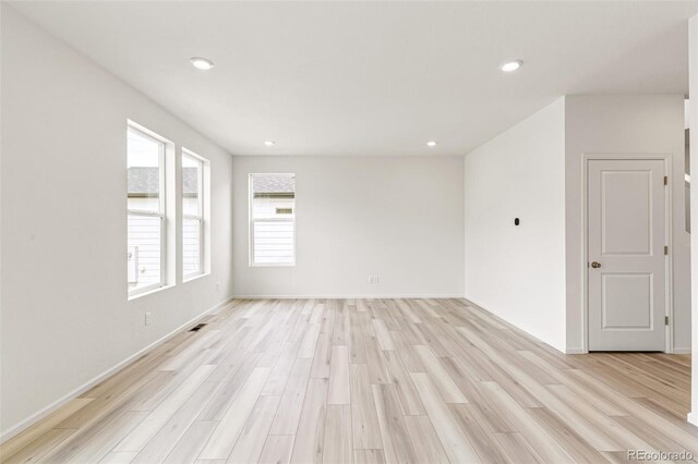 empty room featuring recessed lighting, light wood-style flooring, baseboards, and visible vents