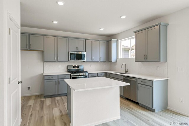 kitchen featuring appliances with stainless steel finishes, light wood-style floors, gray cabinetry, and a sink