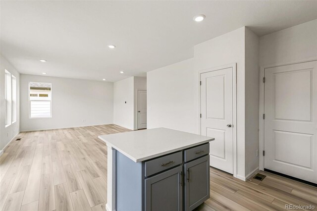 kitchen with gray cabinetry, a center island, light countertops, recessed lighting, and light wood-style floors