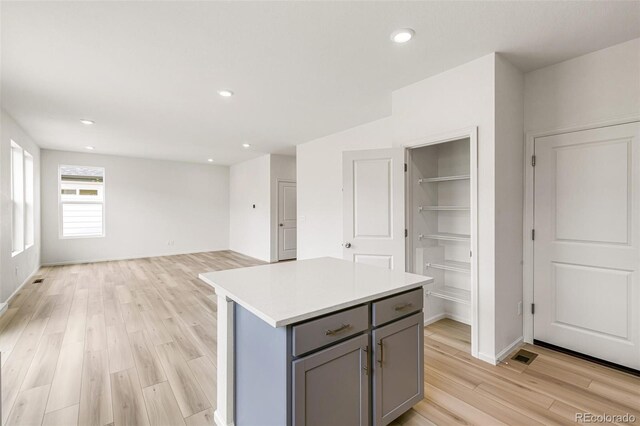 kitchen featuring a kitchen island, light wood-style flooring, recessed lighting, gray cabinetry, and light countertops