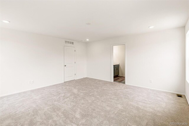 carpeted spare room featuring recessed lighting, visible vents, and baseboards