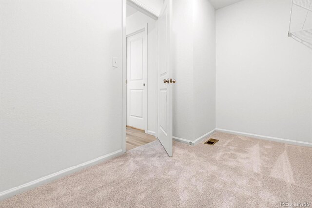 unfurnished room with visible vents, baseboards, and light colored carpet