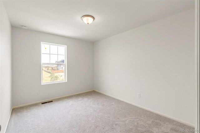 carpeted spare room with visible vents and baseboards