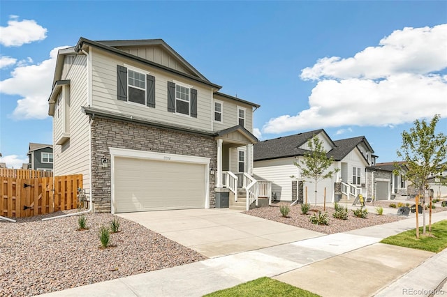 view of front of property featuring fence, concrete driveway, a garage, stone siding, and board and batten siding