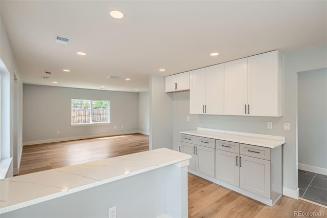 6000 Yarrow St, Arvada, CO 80004 - kitchen featuring light stone countertops, recessed lighting, white cabinetry, baseboards, and light wood-type flooring
