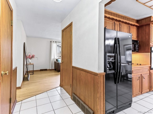 kitchen featuring light tile patterned floors, visible vents, brown cabinets, light countertops, and black appliances