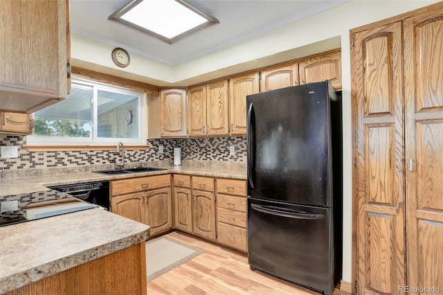 kitchen featuring sink, light hardwood / wood-style flooring, ornamental molding, decorative backsplash, and black appliances