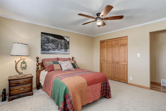 carpeted bedroom with crown molding, ceiling fan, a closet, and a textured ceiling