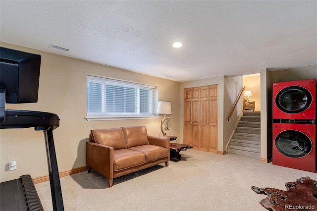 interior space with light colored carpet, stacked washer / dryer, and a textured ceiling