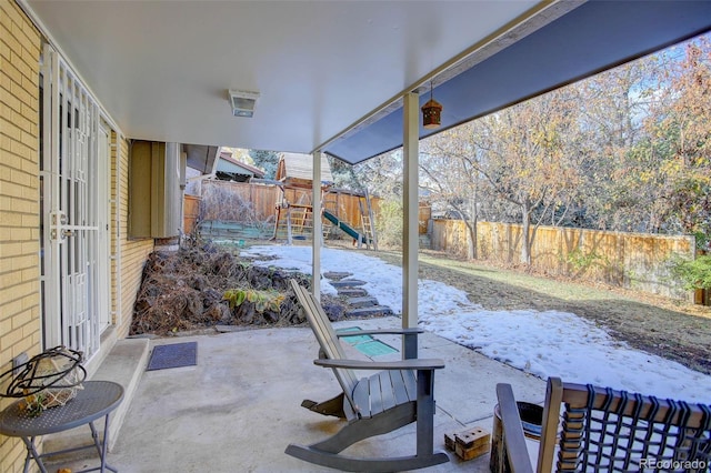 snow covered patio with a playground