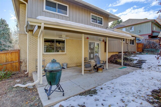 snow covered back of property with a patio area