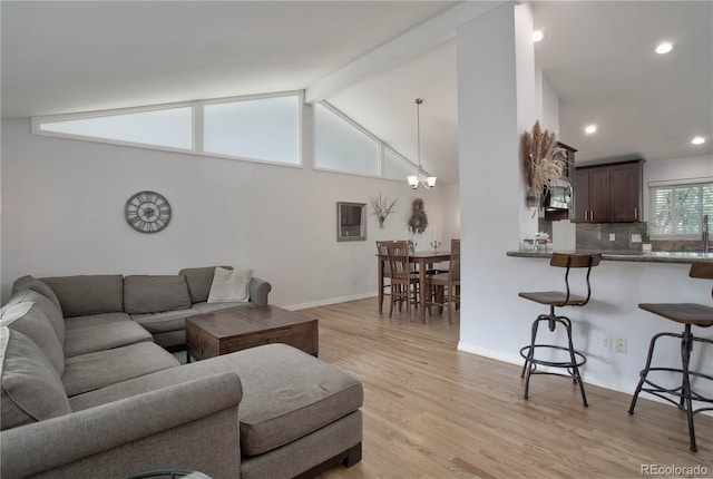 living room featuring a chandelier, lofted ceiling with beams, and light hardwood / wood-style floors