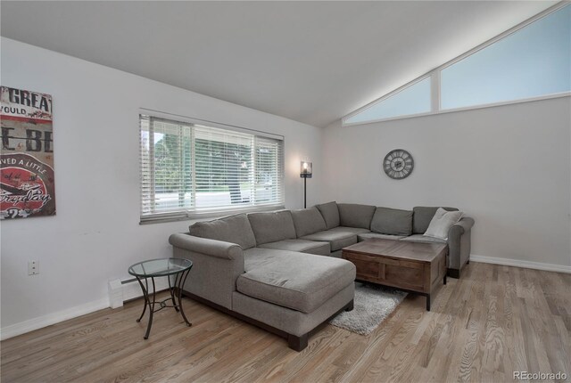 living room with light hardwood / wood-style floors, lofted ceiling, and a baseboard heating unit