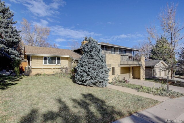 view of front of property featuring a garage, a balcony, and a front lawn