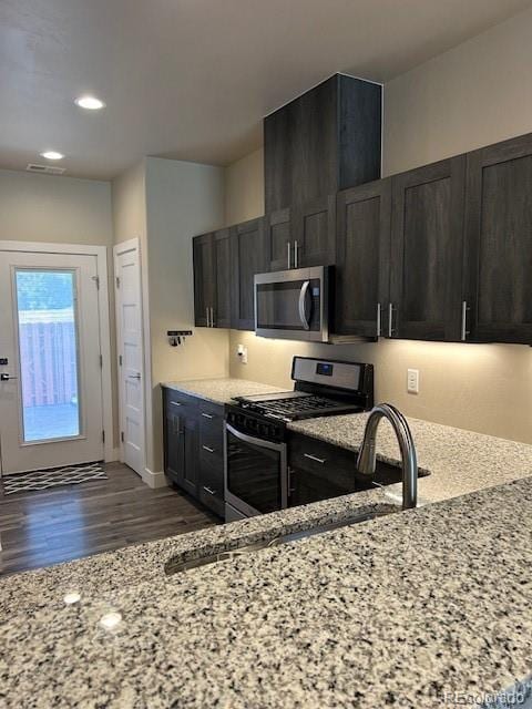 kitchen featuring light stone counters, appliances with stainless steel finishes, and dark wood-type flooring