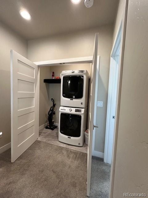 laundry room with carpet flooring and stacked washer / drying machine