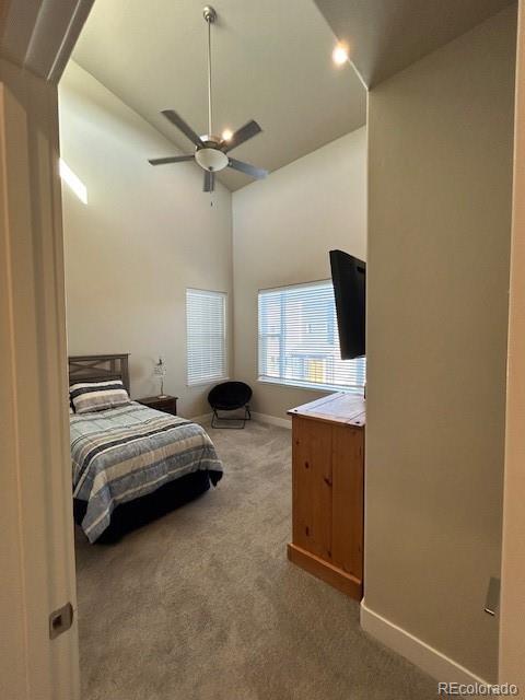 carpeted bedroom featuring high vaulted ceiling and ceiling fan